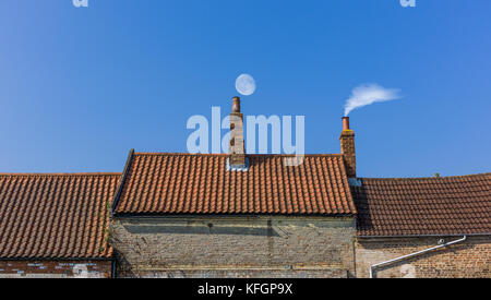 Schornstein-Dachlinie mit Mond und Rauch Stockfoto