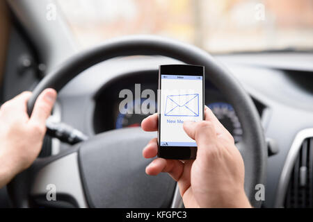 Mann Hält Mobiltelefon Mit Nachrichtenbenachrichtigung Während Der Fahrt Mit Dem Auto Stockfoto