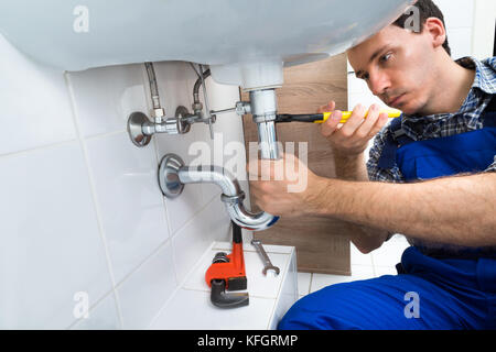 Portrait of Male Plumber Fixing A sink in Bathroom Stockfoto