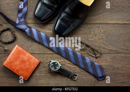 Overhead shot der Mode Männer lifestyle Konzept Hintergrund. Leder schwarz Schuh & Geldbörse mit wesentlichen Zubehör auf modernen, rustikalen braunen Tisch zu reisen Stockfoto