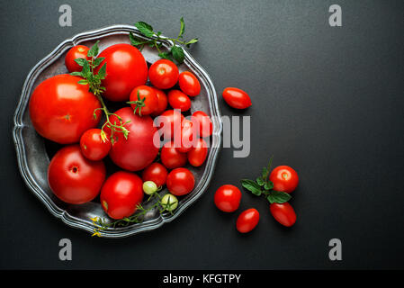 Frische rote Tomaten in eine Schüssel auf schwarzem Hintergrund. top View Stockfoto