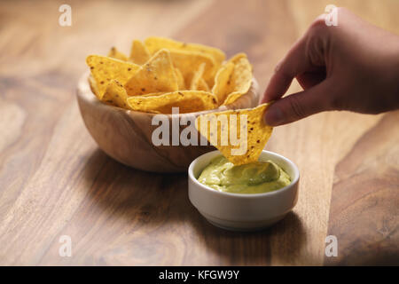 Junge weibliche Hand tauchen Nachos in guacamole Sauce, flachen Fokus Stockfoto