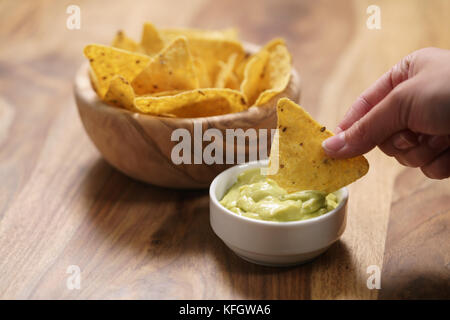 Junge weibliche Hand tauchen Nachos in guacamole Sauce, flachen Fokus Stockfoto