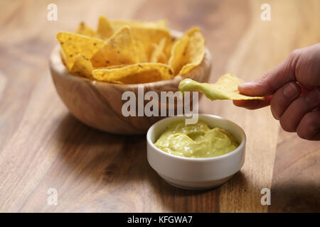 Junge weibliche Hand tauchen Nachos in guacamole Sauce, flachen Fokus Stockfoto