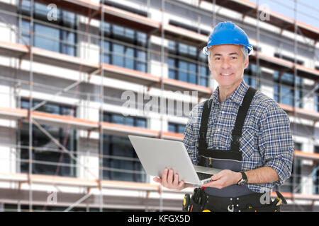 Portrait von Senior Architekt mit Laptop gegen Gebäude Stockfoto