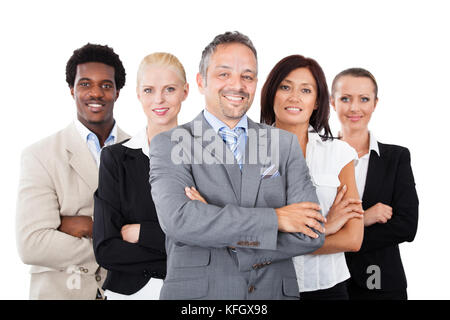 Portrait von zuversichtlich Geschäftsmann ständigen Arme mit Multiethnischen Mannschaft über weißen Hintergrund gekreuzt Stockfoto