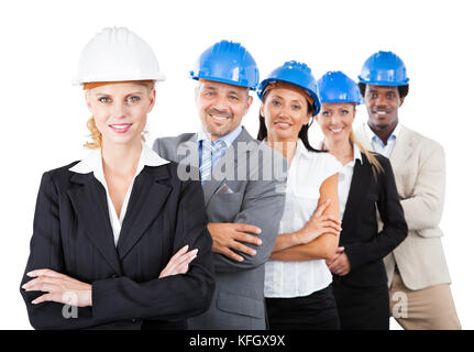 Portrait von Multiethnischen Architekten hardhats tragen beim Stehen Waffen gegen weißen Hintergrund gekreuzt Stockfoto