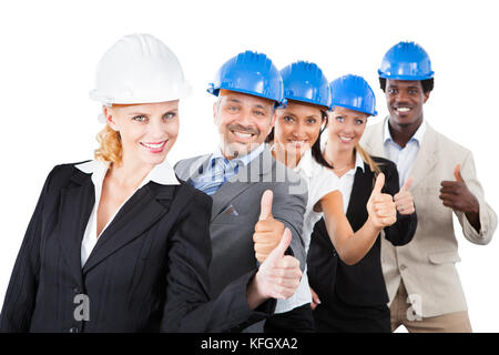Portrait von Multiethnischen Architekten hardhats tragen während Gestik thumbsup vor weißem Hintergrund Stockfoto