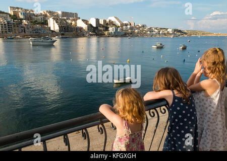 Drei junge Schwestern/Mädchen/Kinder/Kinder/kid Blick über St. Paul's Bay/St. Paul's Bay/Xemxija Bay, im Norden von Malta aus Triq San Pawl. Stockfoto