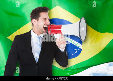 Geschäftsmann Schreien über Megaphon vor der brasilianischen Flagge Stockfoto