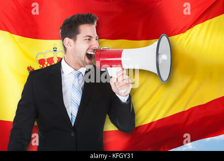 Geschäftsmann Schreien über Megaphon vor der spanischen Flagge Stockfoto