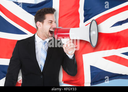 Porträt eines Geschäftsmannes Schreien über Megaphon vor der britischen Flagge Stockfoto