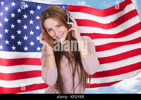 Frau zuhören Erlernen der englischen Sprache Kurs Hörbuch vor der amerikanischen Flagge Stockfoto