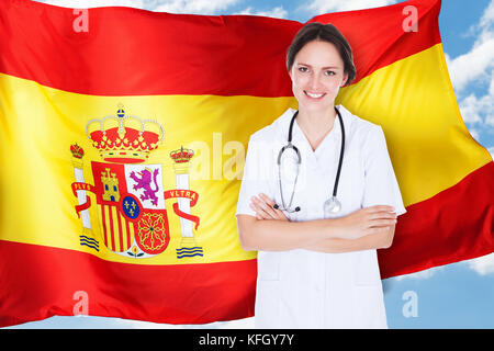 Junge Ärztin Mit Gekreuzter Armlehne, Die Vor Der Spanischen Flagge Steht Stockfoto