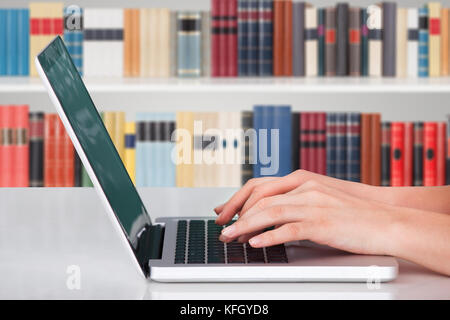 Nahaufnahme einer Person, die in der Bibliothek ein Notizbuch tippt Stockfoto