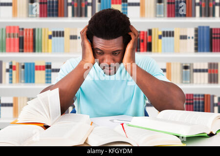 Beunruhigte Afrikanische Studentin, Die Bücher Am Schreibtisch In Der Bibliothek Ansieht Stockfoto