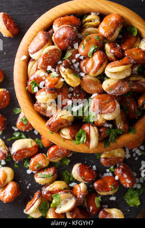 Aperitif des knusprig gebratener gesalzen Bohnen in eine Schüssel close-up auf einem Tisch. Senkrechte Draufsicht von oben Stockfoto