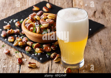 Glas helles Bier mit Vorspeise aus knusprig gebratener gesalzen Bohnen close-up auf Tisch. Horizontale Stockfoto