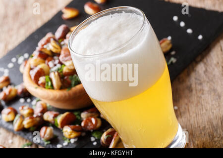 Glas helles Bier und knusprig gebratener gesalzen Bohnen close-up auf einem Tisch. Horizontale Stockfoto
