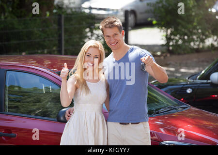 Volle Länge Portrait von glückliches junges Paar Gedrückthalten der Taste durch neues Auto Stockfoto