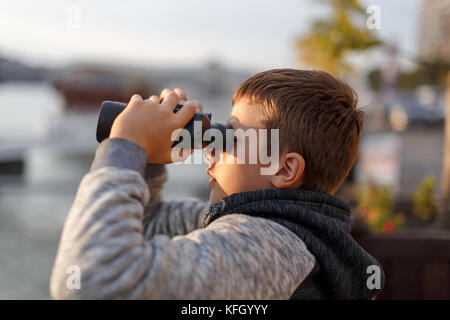 Wenig kaukasischen Jungen beobachten, suchen, schauen, auf der Suche nach durch Fernglas Stockfoto