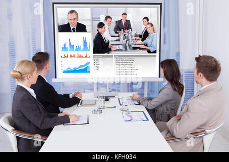 Gruppe von Geschäftsleuten die Teilnahme an Videokonferenzen am Tisch im Büro Stockfoto