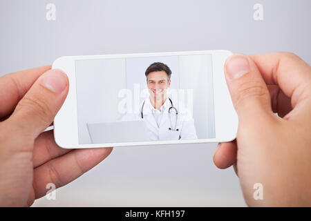 Mann, video chat mit Arzt auf dem Smartphone Stockfoto