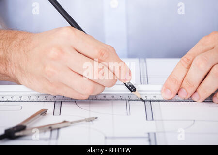 Zugeschnittenes Bild der männlichen Architekten auf Blueprint am Schreibtisch im Büro arbeiten Stockfoto