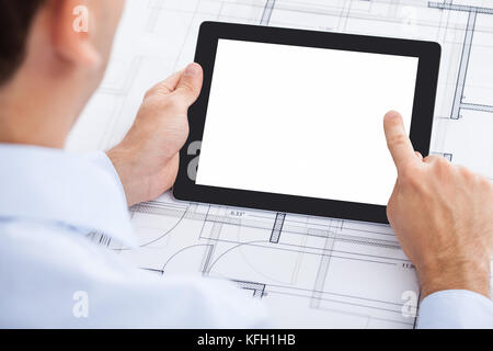 Zugeschnittenes Bild des Geschäftsmannes Holding leer digital Tablet über Blueprint im Büro Stockfoto