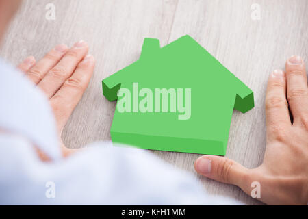 Bild der Geschäftsmann bildet Hand Rahmen um Gewächshaus Modell am Schreibtisch beschnitten Stockfoto