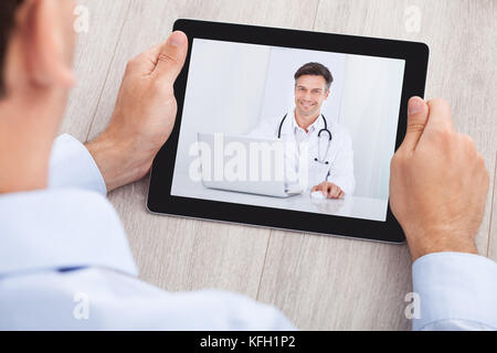 Bild von Geschäftsmann Videokonferenzen mit Arzt auf digital-Tablette am Schreibtisch im Büro beschnitten Stockfoto