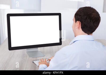 Rückansicht der Geschäftsmann mit Desktop-PC am Schreibtisch im Büro Stockfoto