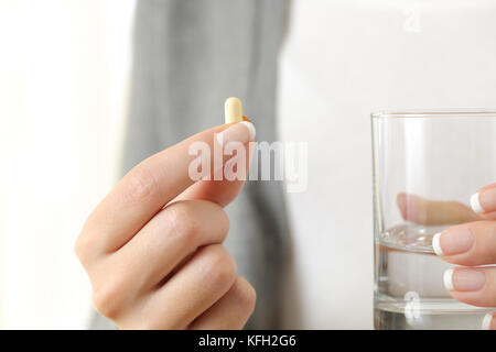 Nahaufnahme eines Mädchens Hand eine Pille und ein Glas Wasser Stockfoto