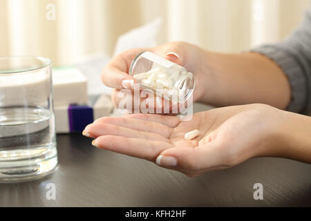 Nahaufnahme einer Frau, die eine Pille aus der Flasche auf einem Tisch Stockfoto