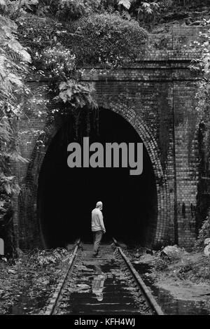 Einstehender Mann steht vor einem verlassenen Zugtunnel Stockfoto