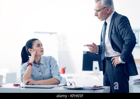 Mad Geschäftsmann schrie seine junge weibliche Mitarbeiter Stockfoto