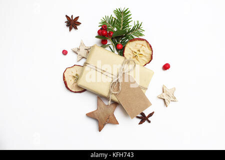 Weihnachten festlich gestalteten Lager Bildkomposition. handgefertigte Geschenkbox mit Handwerk Papier tag, Beeren, Holz- Sterne, getrocknete Äpfel und Fir Tree Branch auf weißem Holz- Hintergrund. Flach, Ansicht von oben. Stockfoto