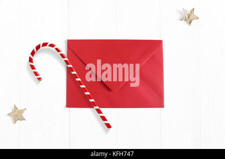 Weihnachten mockup Szene mit roten Umschlag, Zuckerstange Dekoration und Sterne aus Birkenrinde auf weißem Holz- Hintergrund. leeren Raum für Ihren Text, Ansicht von oben. Stockfoto