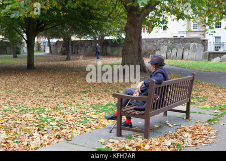 Alter Mann auf der Bank auf dem Gelände von St. George's Deal Kirche mit Grabsteinen um den Umfang herum, Deal, Kent, England, Vereinigtes Königreich, Europa Stockfoto