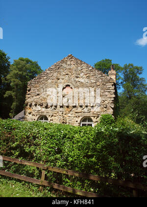 Ein Ferienhaus mit einer alten Steinmauer Fassade auf seinem eigenen Land unter Bäumen, Sträuchern und blauer Himmel. . Stockfoto