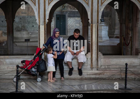 Eine muslimische Familie macht eine Pause, während sie die Mosaikapsis in der Hagia Sophia in Istanbul, Türkei, besucht. Stockfoto