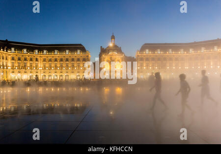 Menschen Silhouetten in Wasser Spiegel, Le Miroir d'Eau, der weltweit größte reflektierende Pool bei Nacht in Place de la Bourse, Burdeaux, Frankreich Stockfoto