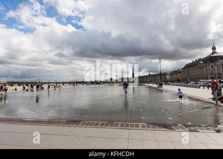 Die Leute genießen den Wasserspiegel, Le Miroir d'Eau, das größte reflektierende Schwimmbad der Welt auf der Place de la Bourse, Burdeaux, Frankreich Stockfoto