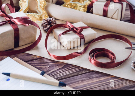 Urlaub Dekorationen und Notebook mit Liste der Geschenke auf dunklen Holzmöbeln rustikal Tisch. Weihnachten Planung Konzept. selektive Fokus Stockfoto