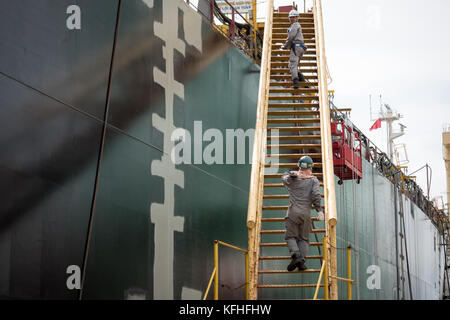 Zwei Arbeiter gehen über die Leiter an Bord des Schiffes im Bau. cam Rahn Werft, Vietnam. Stockfoto