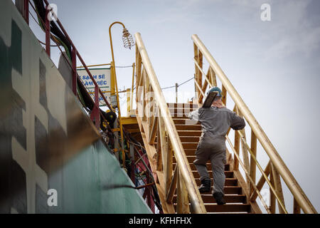 Ein Handwerker steigt die Leiter an Bord des Schiffs im Bau. CAM Rahn Werft, Vietnam. Stockfoto