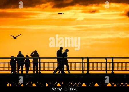 Southport, Merseyside, Sonnenuntergang über Southport Pier. 29. Oktober 2017. UK Wetter. Als halbe Amtszeit nähert sich dem Ende, Familien machen Sie einen Spaziergang entlang der Promenade als atemberaubende Sonnenuntergang schmiegt sich in den Horizont über den berühmten Pier in Southport, Merseyside. Erst im Jahre 1860 eröffnet, es erstreckt sich über eine Länge von 1.108 Meter (3.635 ft) und der Zweitlängste in Großbritannien. Es war grad II am 18. August 1975 aufgeführt. Die Straßenbahn fuhr von der Promenade zum Pier Head zu verschiedenen Zeiten in der Geschichte der Pier, vor kurzem von August 2005 bis Juni 2015. Credit: cernan Elias/Alamy leben Nachrichten Stockfoto