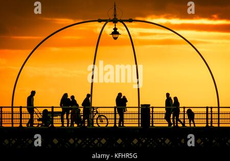 Southport, Merseyside, Sonnenuntergang über Southport Pier. 29. Oktober 2017. UK Wetter. Als halbe Amtszeit nähert sich dem Ende, Familien machen Sie einen Spaziergang entlang der Promenade als atemberaubende Sonnenuntergang schmiegt sich in den Horizont über den berühmten Pier in Southport, Merseyside. Erst im Jahre 1860 eröffnet, es erstreckt sich über eine Länge von 1.108 Meter (3.635 ft) und der Zweitlängste in Großbritannien. Es war grad II am 18. August 1975 aufgeführt. Die Straßenbahn fuhr von der Promenade zum Pier Head zu verschiedenen Zeiten in der Geschichte der Pier, vor kurzem von August 2005 bis Juni 2015. Credit: cernan Elias/Alamy leben Nachrichten Stockfoto