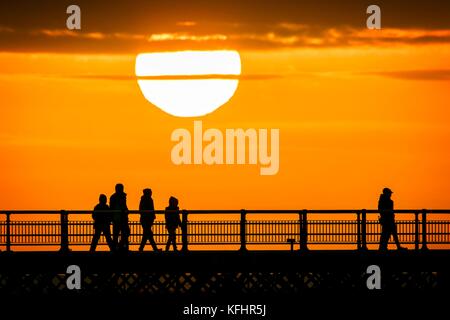 Southport, Merseyside, Sonnenuntergang über Southport Pier. 29. Oktober 2017. UK Wetter. Als halbe Amtszeit nähert sich dem Ende, Familien machen Sie einen Spaziergang entlang der Promenade als atemberaubende Sonnenuntergang schmiegt sich in den Horizont über den berühmten Pier in Southport, Merseyside. Erst im Jahre 1860 eröffnet, es erstreckt sich über eine Länge von 1.108 Meter (3.635 ft) und der Zweitlängste in Großbritannien. Es war grad II am 18. August 1975 aufgeführt. Die Straßenbahn fuhr von der Promenade zum Pier Head zu verschiedenen Zeiten in der Geschichte der Pier, vor kurzem von August 2005 bis Juni 2015. Credit: cernan Elias/Alamy leben Nachrichten Stockfoto