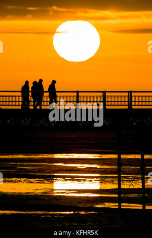 Southport, Merseyside, Sonnenuntergang über Southport Pier. 29. Oktober 2017. UK Wetter. Als halbe Amtszeit nähert sich dem Ende, Familien machen Sie einen Spaziergang entlang der Promenade als atemberaubende Sonnenuntergang schmiegt sich in den Horizont über den berühmten Pier in Southport, Merseyside. Erst im Jahre 1860 eröffnet, es erstreckt sich über eine Länge von 1.108 Meter (3.635 ft) und der Zweitlängste in Großbritannien. Es war grad II am 18. August 1975 aufgeführt. Die Straßenbahn fuhr von der Promenade zum Pier Head zu verschiedenen Zeiten in der Geschichte der Pier, vor kurzem von August 2005 bis Juni 2015. Credit: cernan Elias/Alamy leben Nachrichten Stockfoto